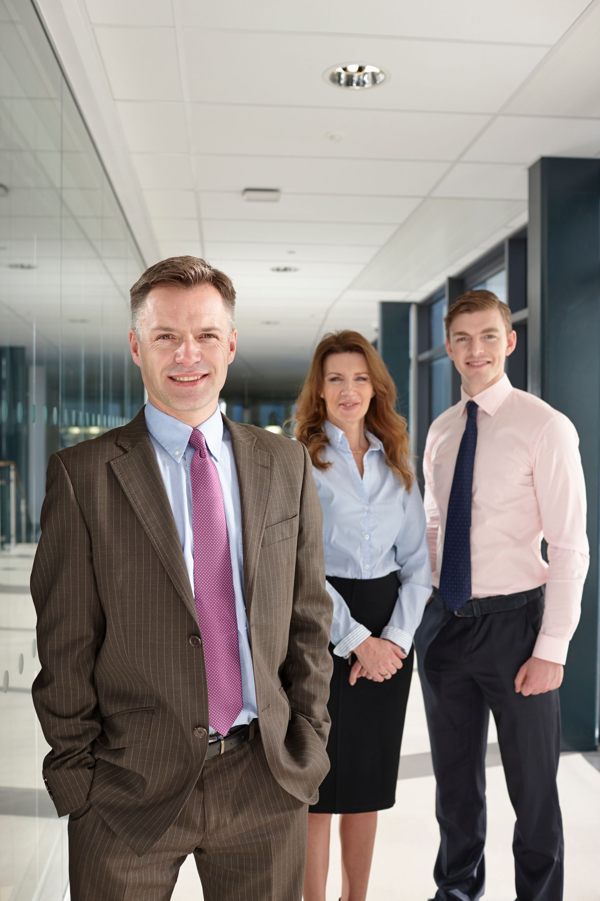 A man in a suit and tie is standing next to two other people