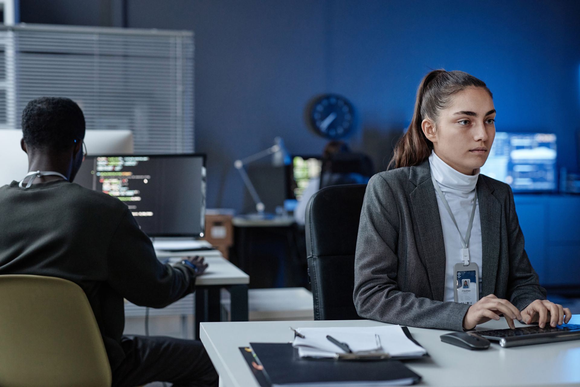 A man and a woman are sitting at a desk in front of computers.