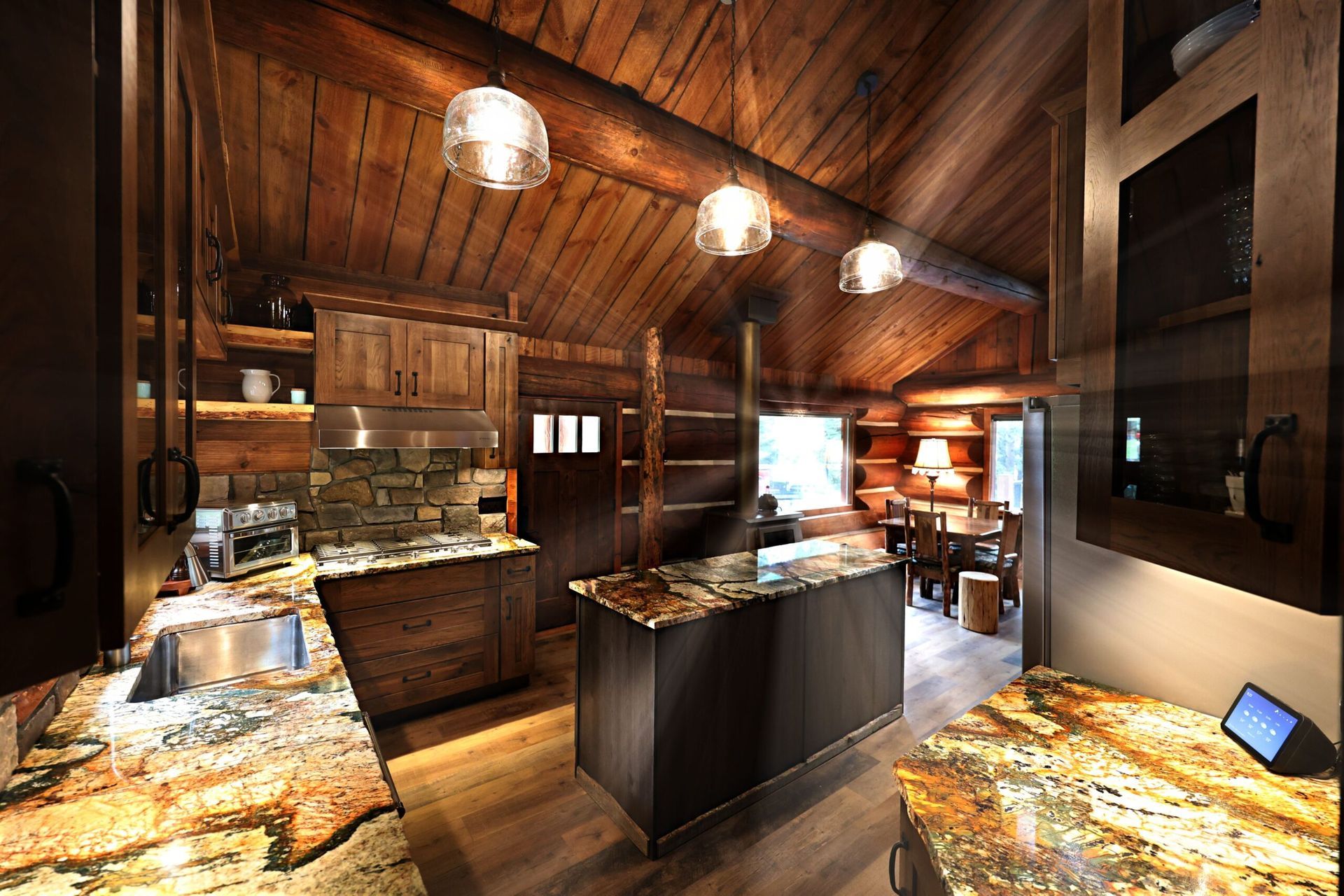 Cozy log cabin kitchen with wood cabinets, granite countertops, and a center island.