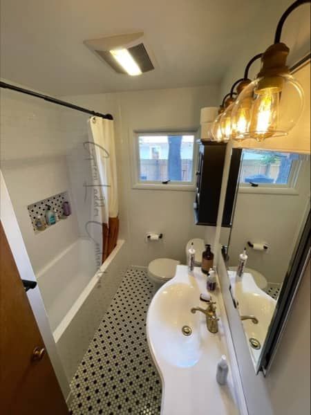 Bathroom with black and white tiled floor, white sink, and vintage light fixture.