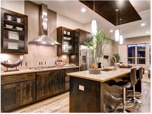 Modern kitchen with dark wood cabinets, stainless steel appliances, and an island with bar stools.