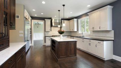 Modern kitchen with white and dark wood cabinets, island, dark floors, and blue accent wall.