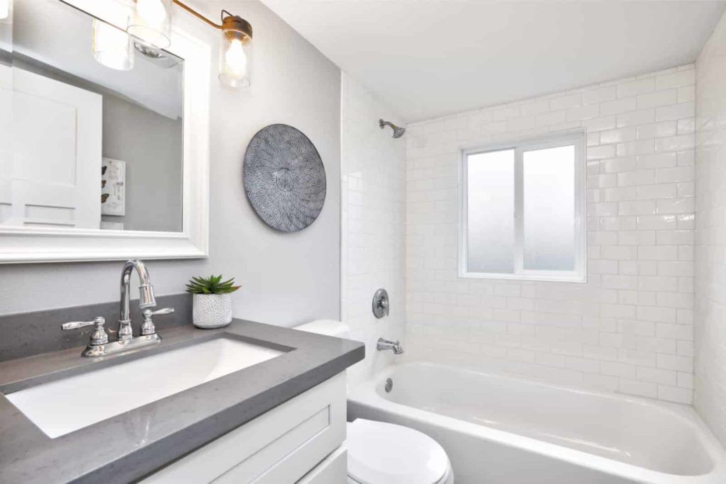 Bathroom with white subway tile, gray countertop, and a round wall art.