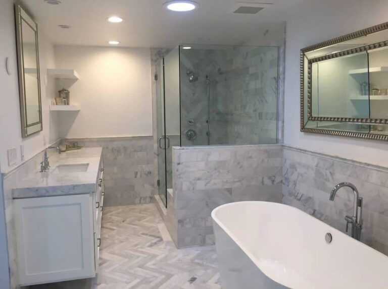 Spacious, modern bathroom with marble tile, a freestanding tub, and a glass shower.