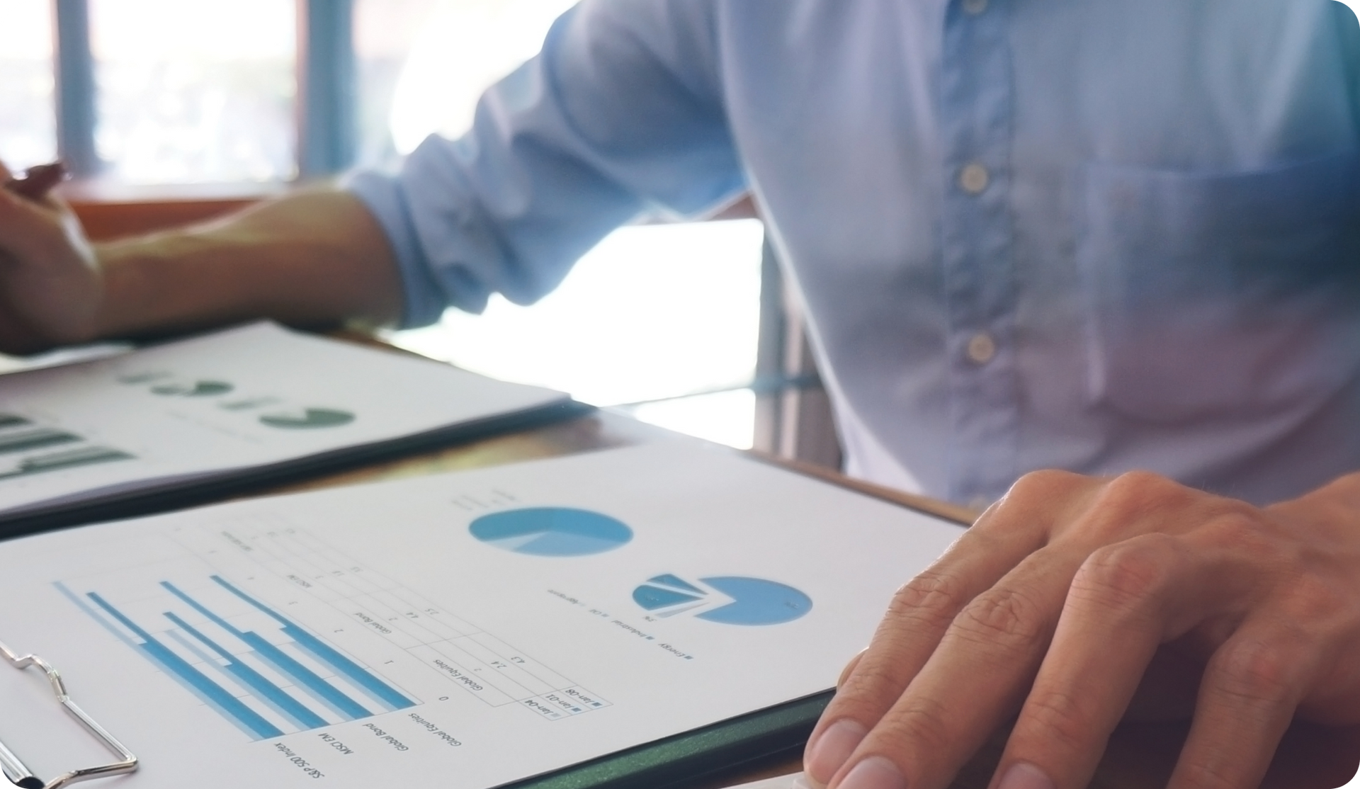 Person analyzing financial charts on a desk.