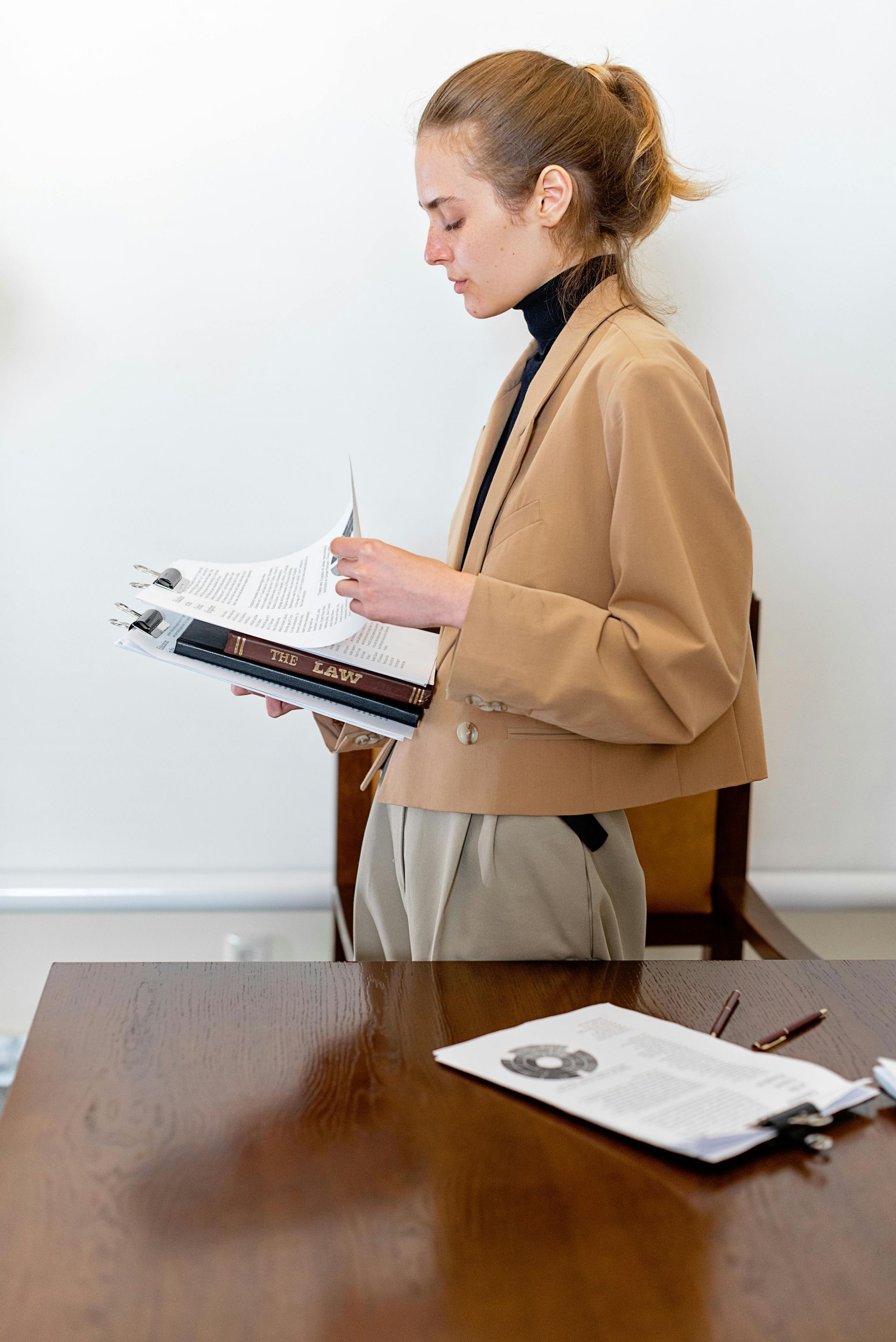 A woman is sitting at a desk holding a clipboard and a pen.