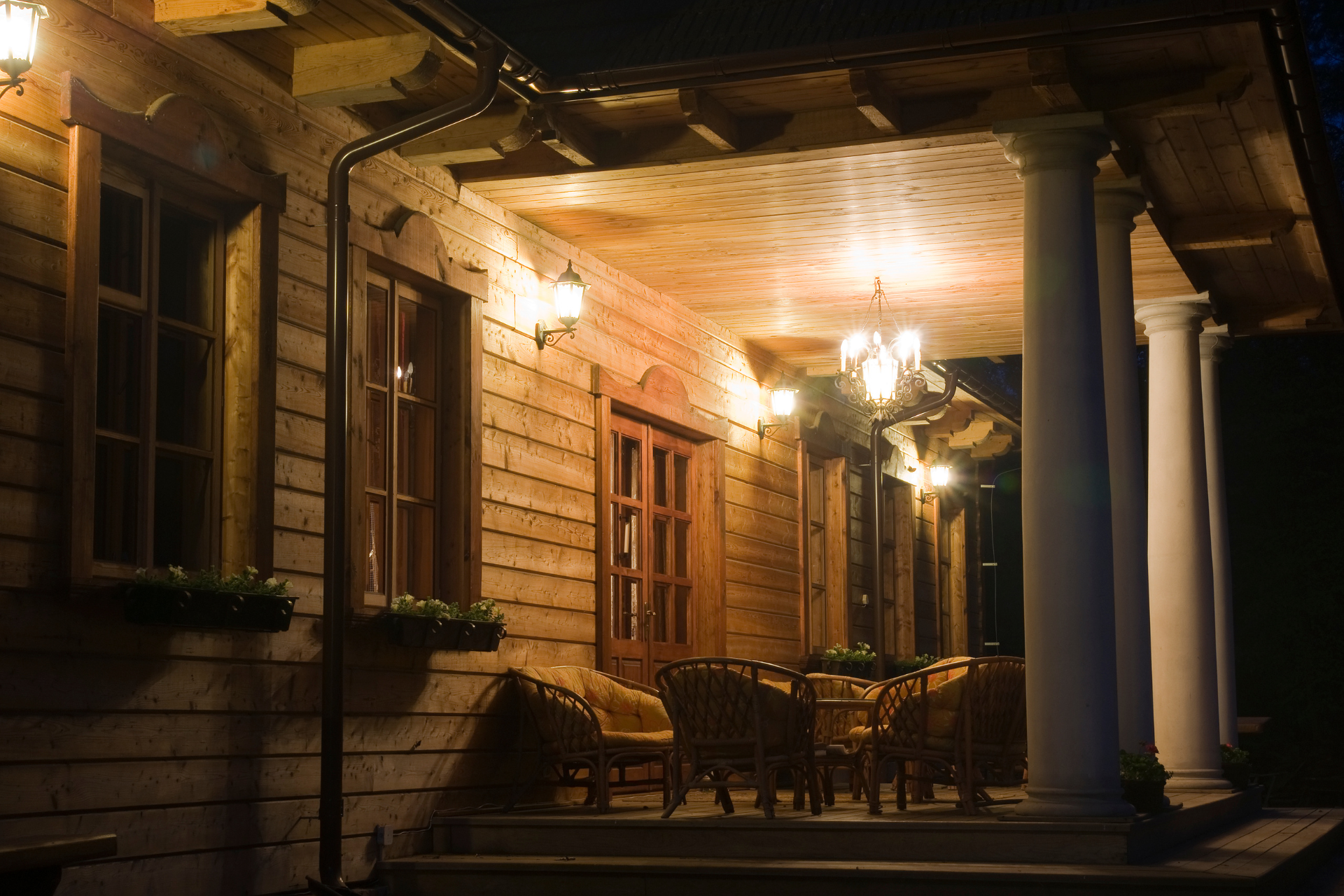 The porch of a wooden house is lit up at night