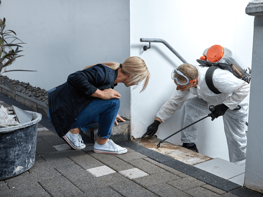 a woman is kneeling down next to a man in a protective suit .