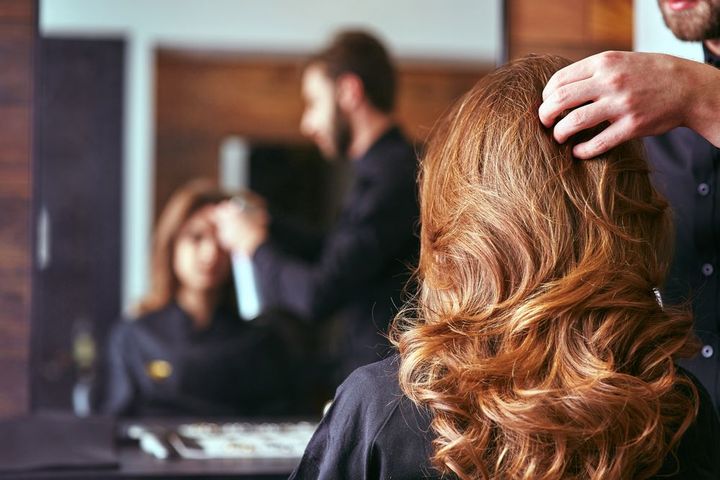 A woman is getting her hair done by a hairdresser in a salon.
