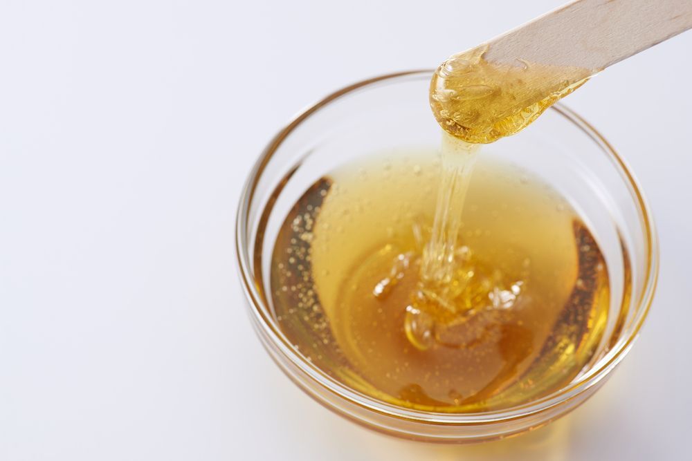 A bowl of honey with a spatula sticking out of it.