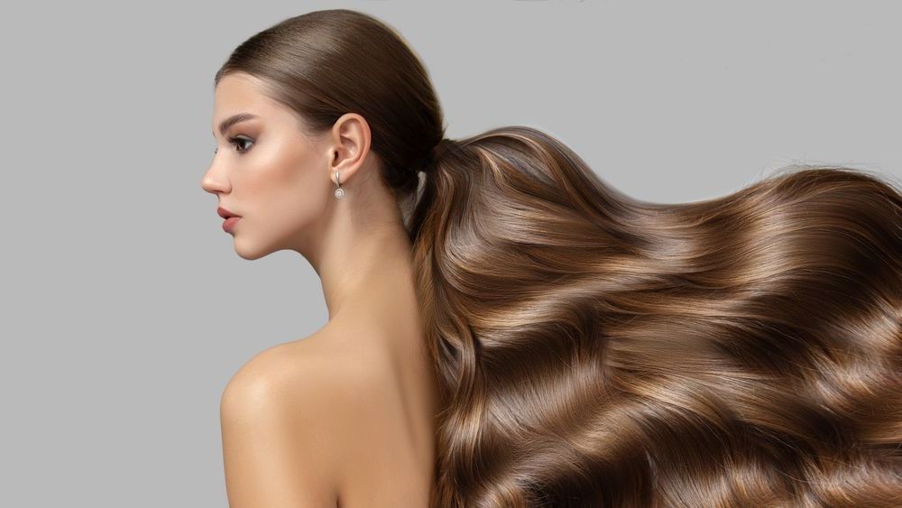 A woman with very long hair is wearing a ponytail.