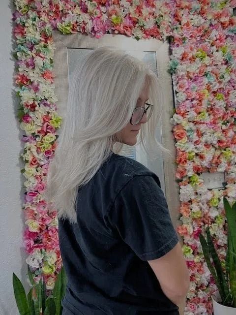 A woman is standing in front of a wall of flowers