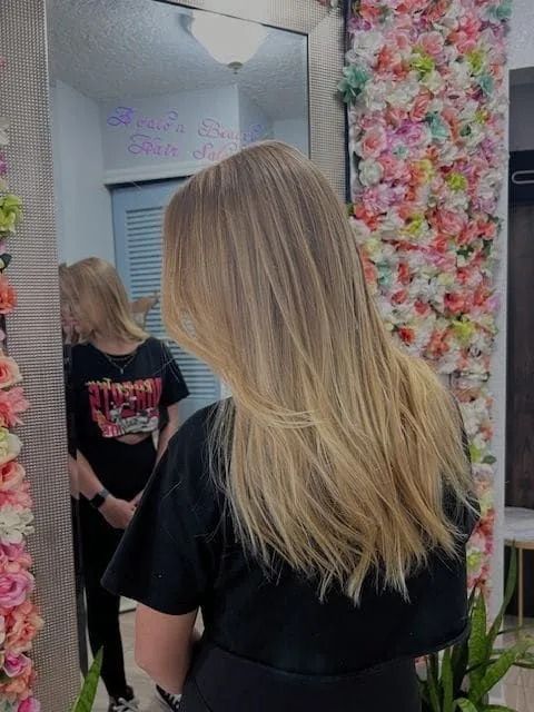 A woman with long blonde hair is standing in front of a mirror.