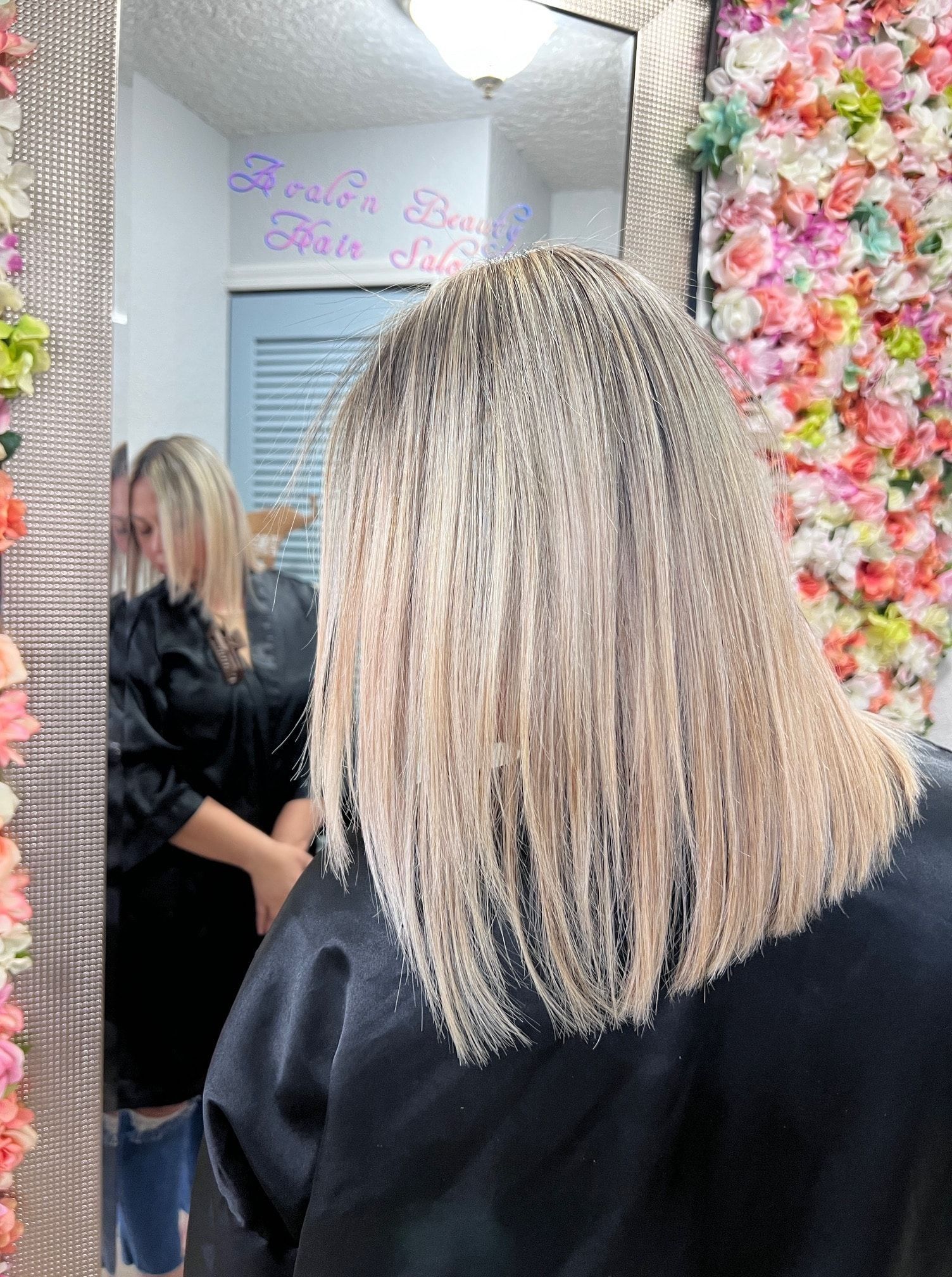 A woman is getting her hair cut in front of a mirror in a salon.
