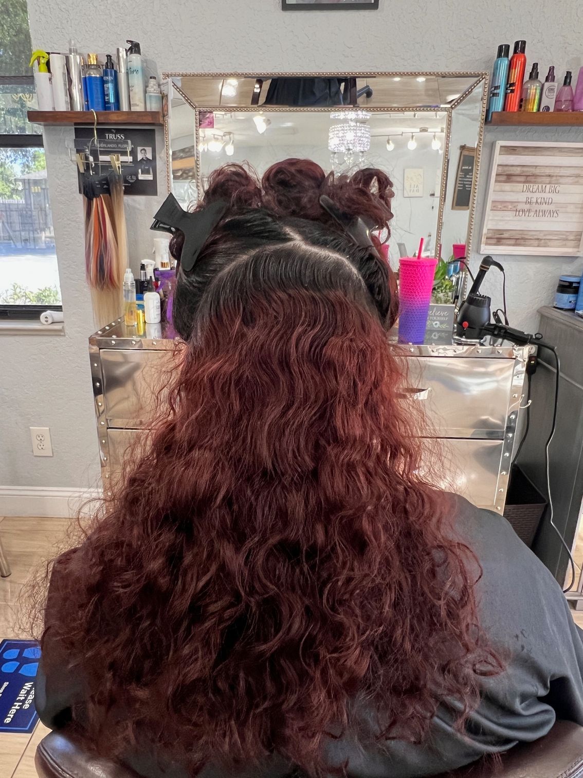 A woman with red curly hair is sitting in a chair in a salon.