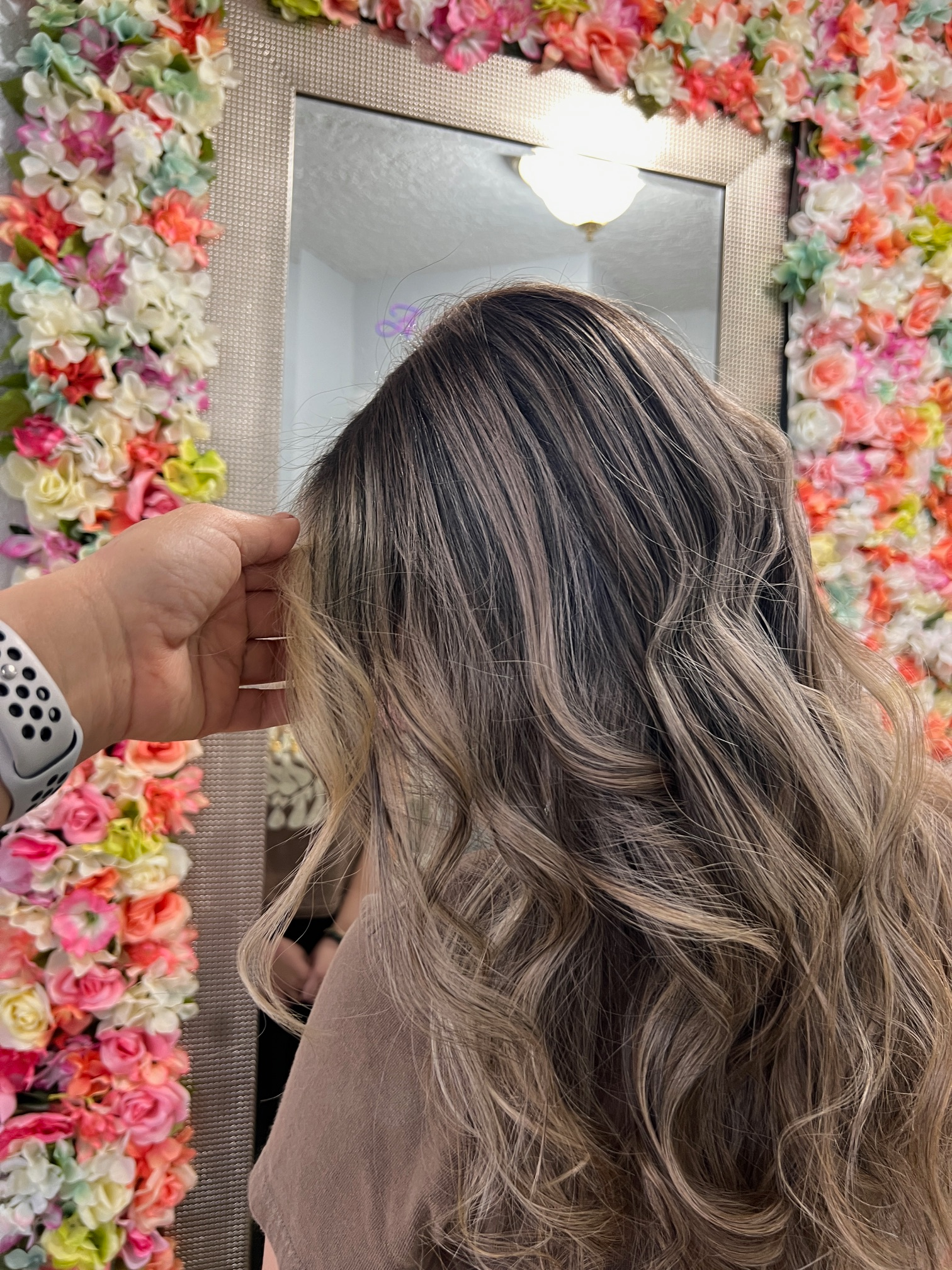 A person is touching a woman 's hair in front of a mirror.