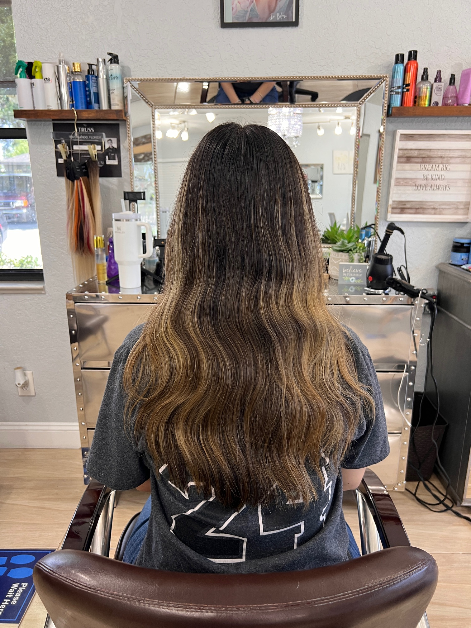 A woman is sitting in a chair in a hair salon.