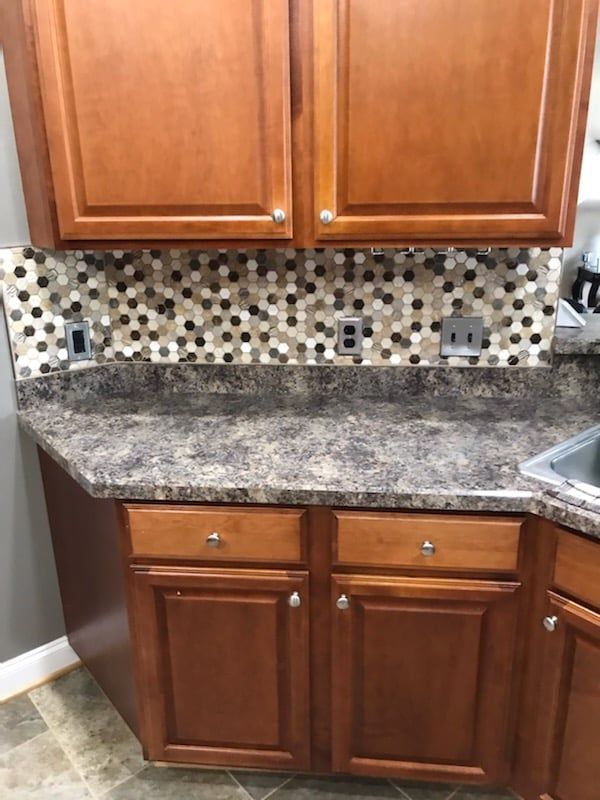 A kitchen with wooden cabinets , granite counter tops , and a sink.
