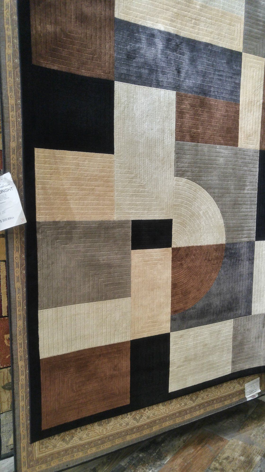 A rug with a geometric pattern is sitting on a wooden floor.