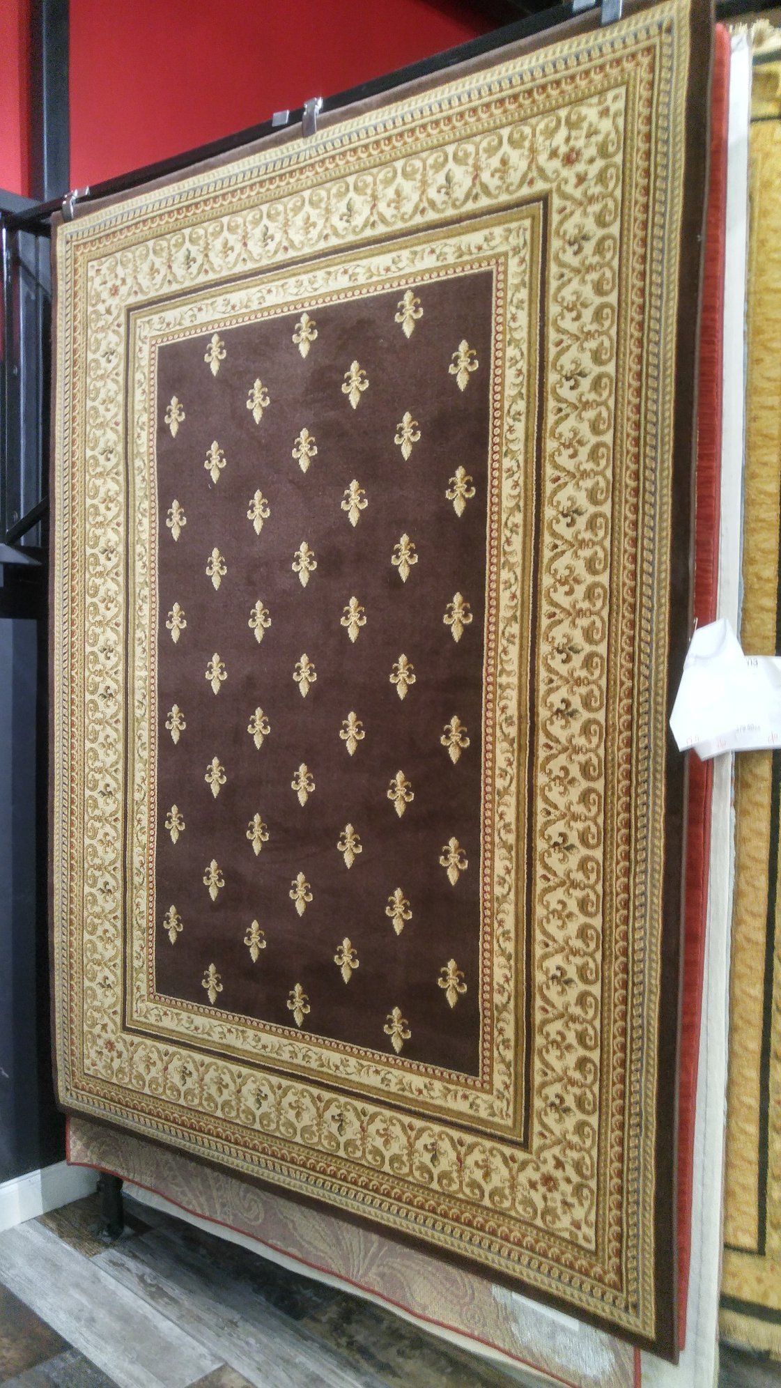 A brown rug with a gold border is sitting on top of a wooden floor.