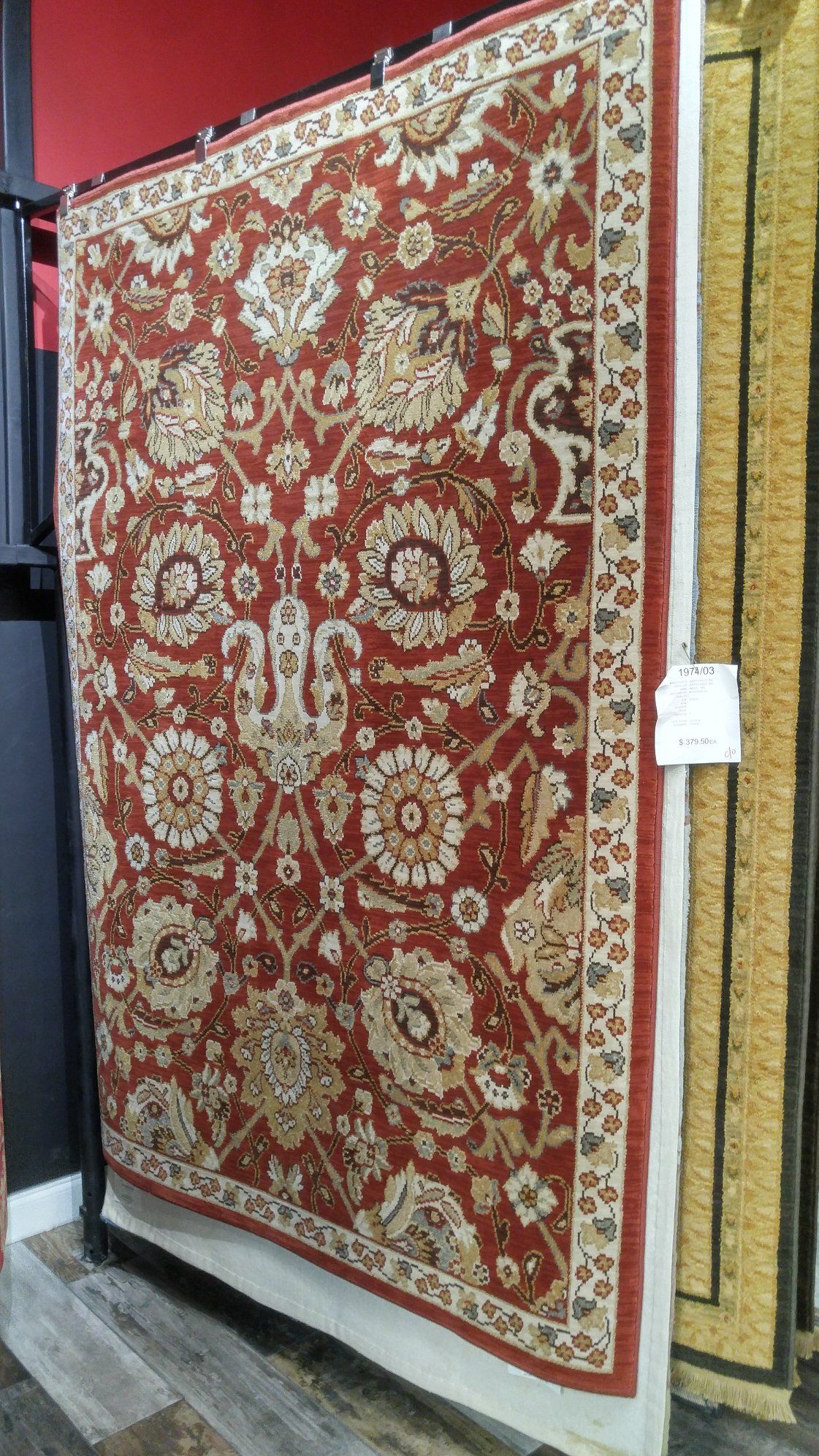 A red rug is hanging on a rack in a store.