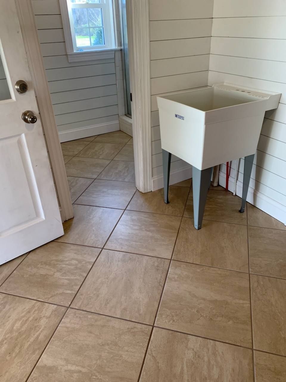 A laundry room with a sink and tile floor.