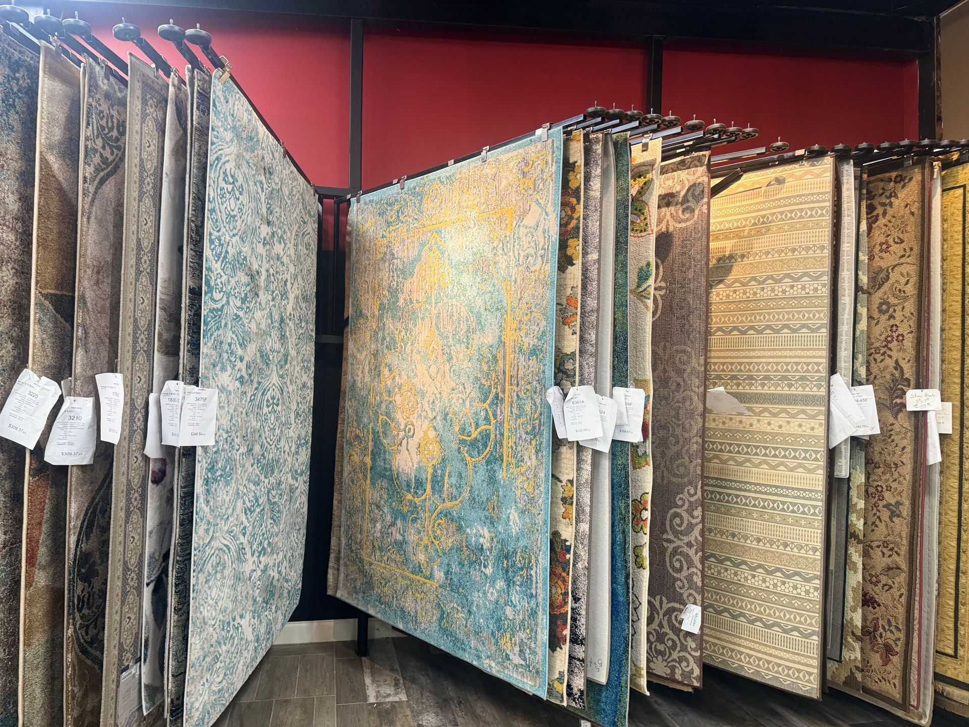 A row of rugs hanging on a rack in a store.