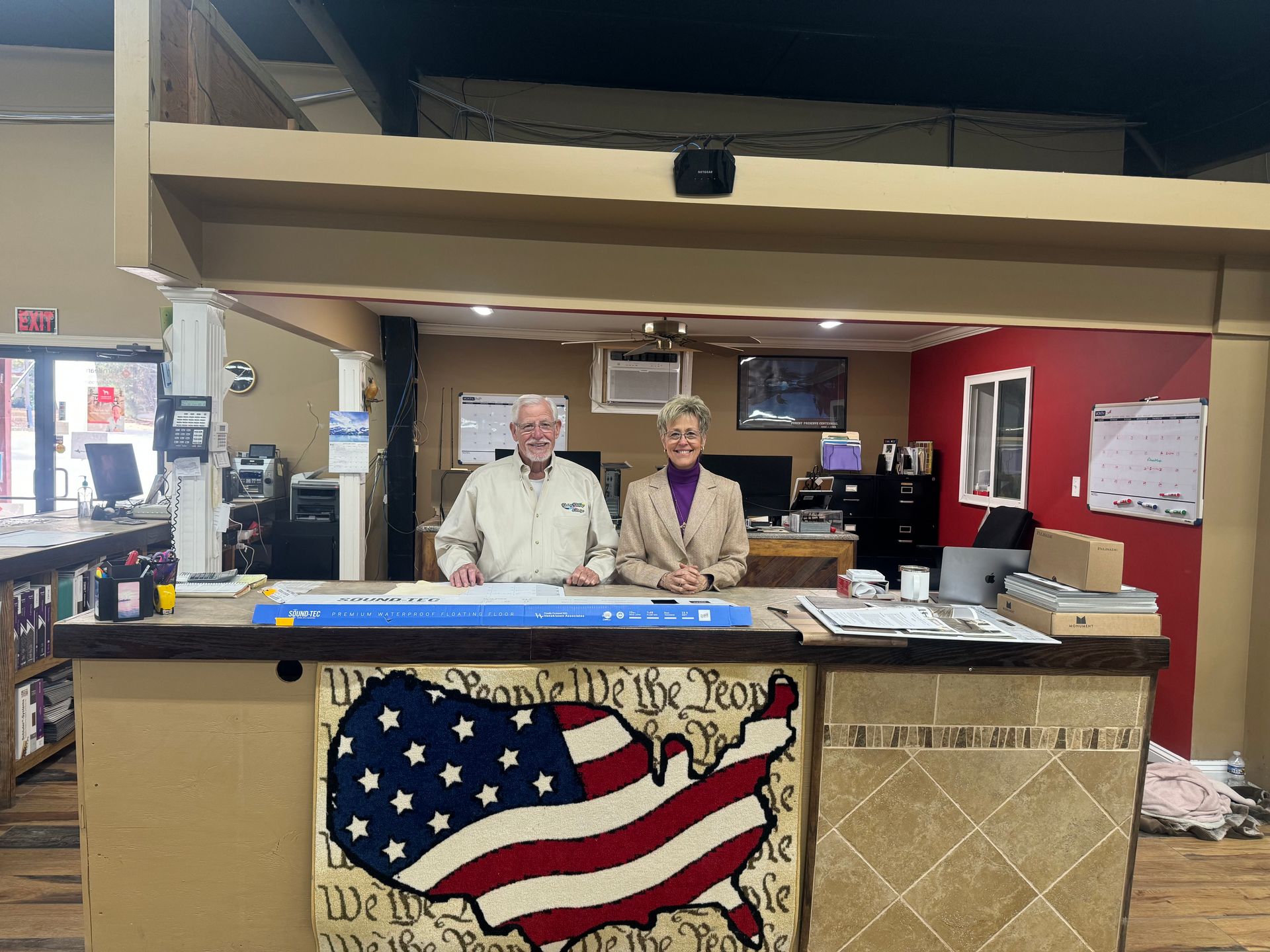 A man and a woman are standing in front of a counter with an american flag on it.
