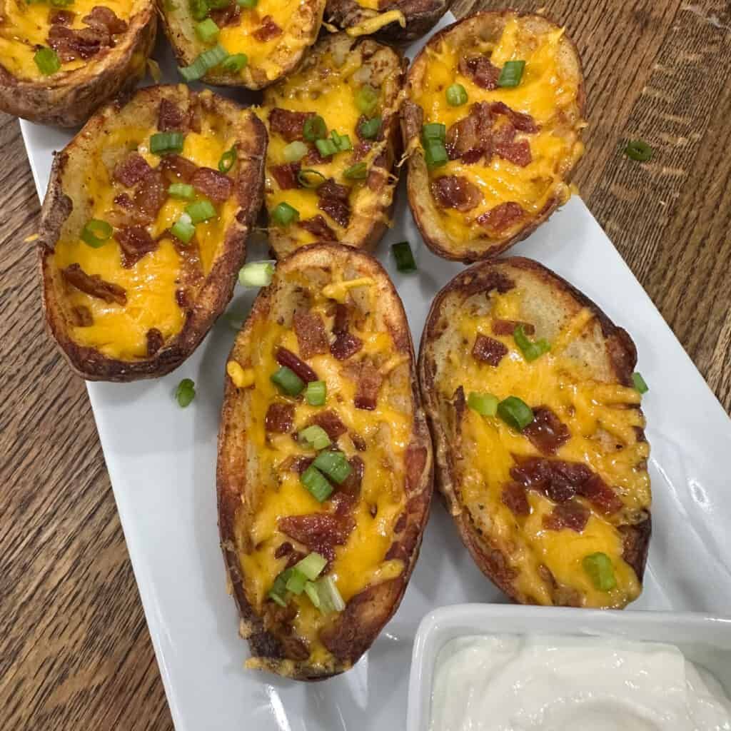A white plate topped with potato skins covered in cheese and bacon.