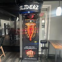 A boxing machine is sitting in a room next to a table and chairs.