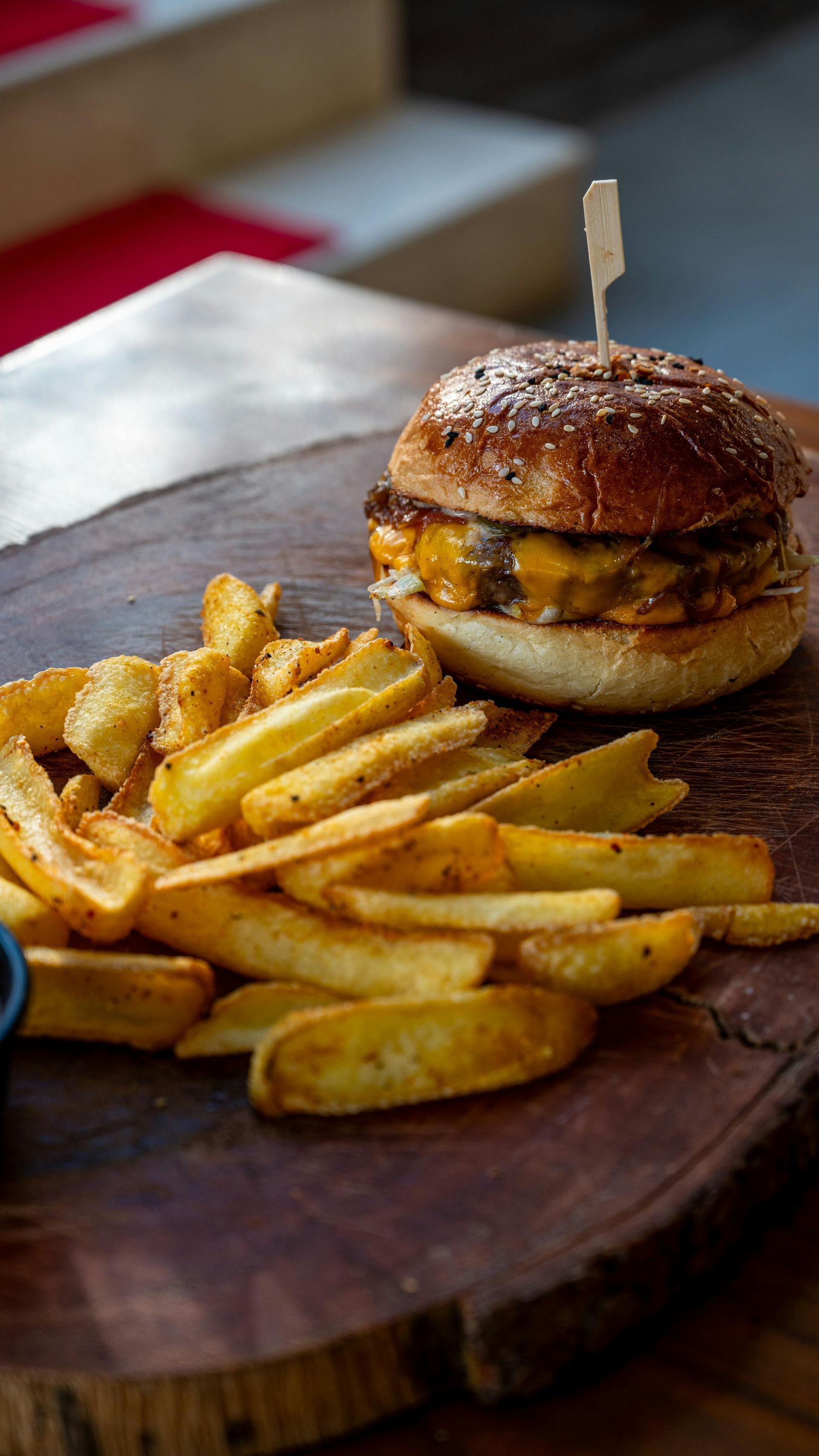 A hamburger and french fries on a wooden cutting board.