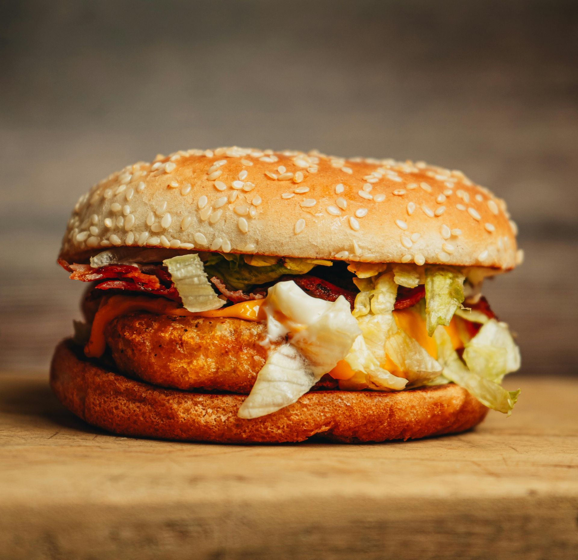 A close up of a chicken sandwich on a wooden cutting board.