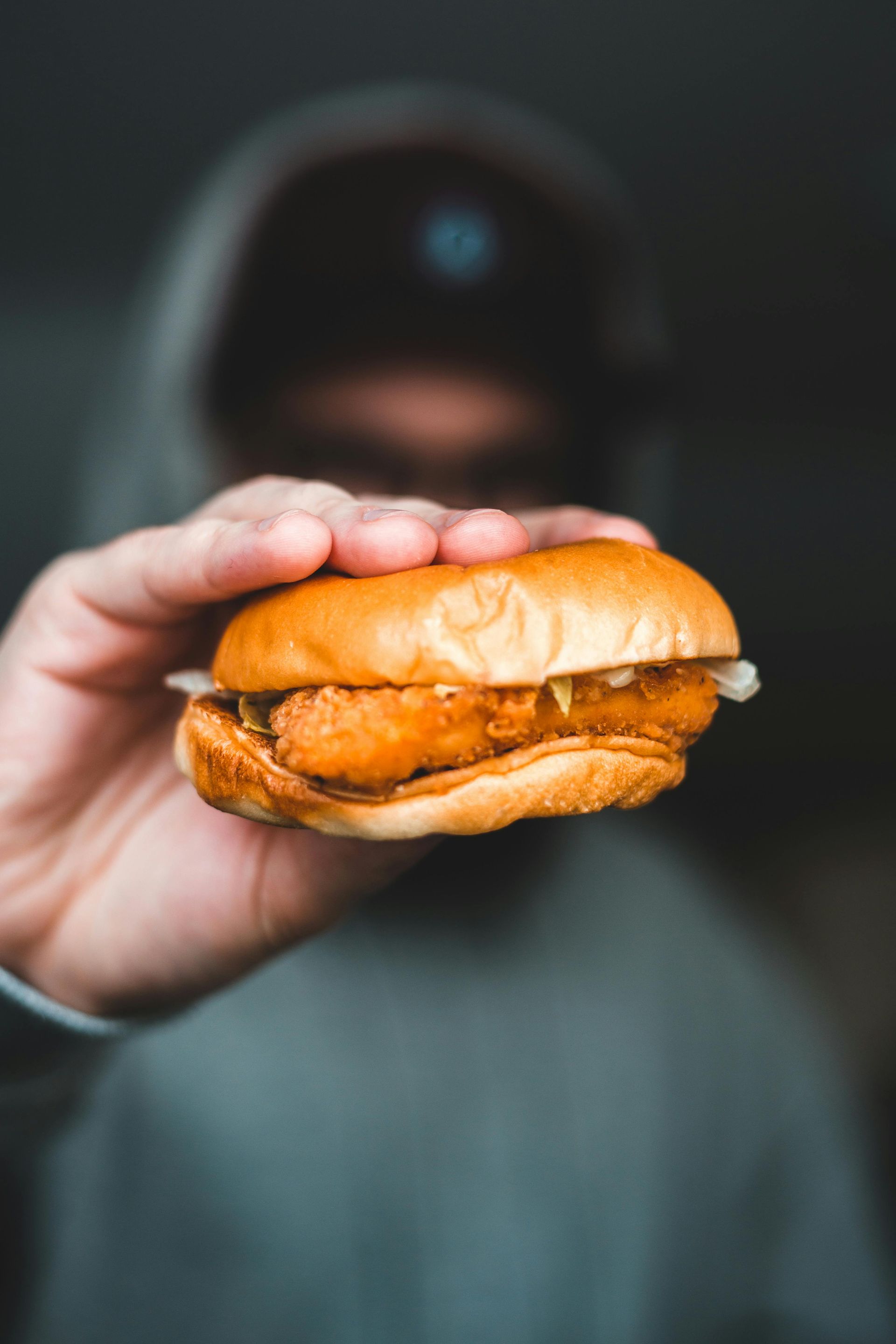 A person is holding a chicken sandwich in their hand.