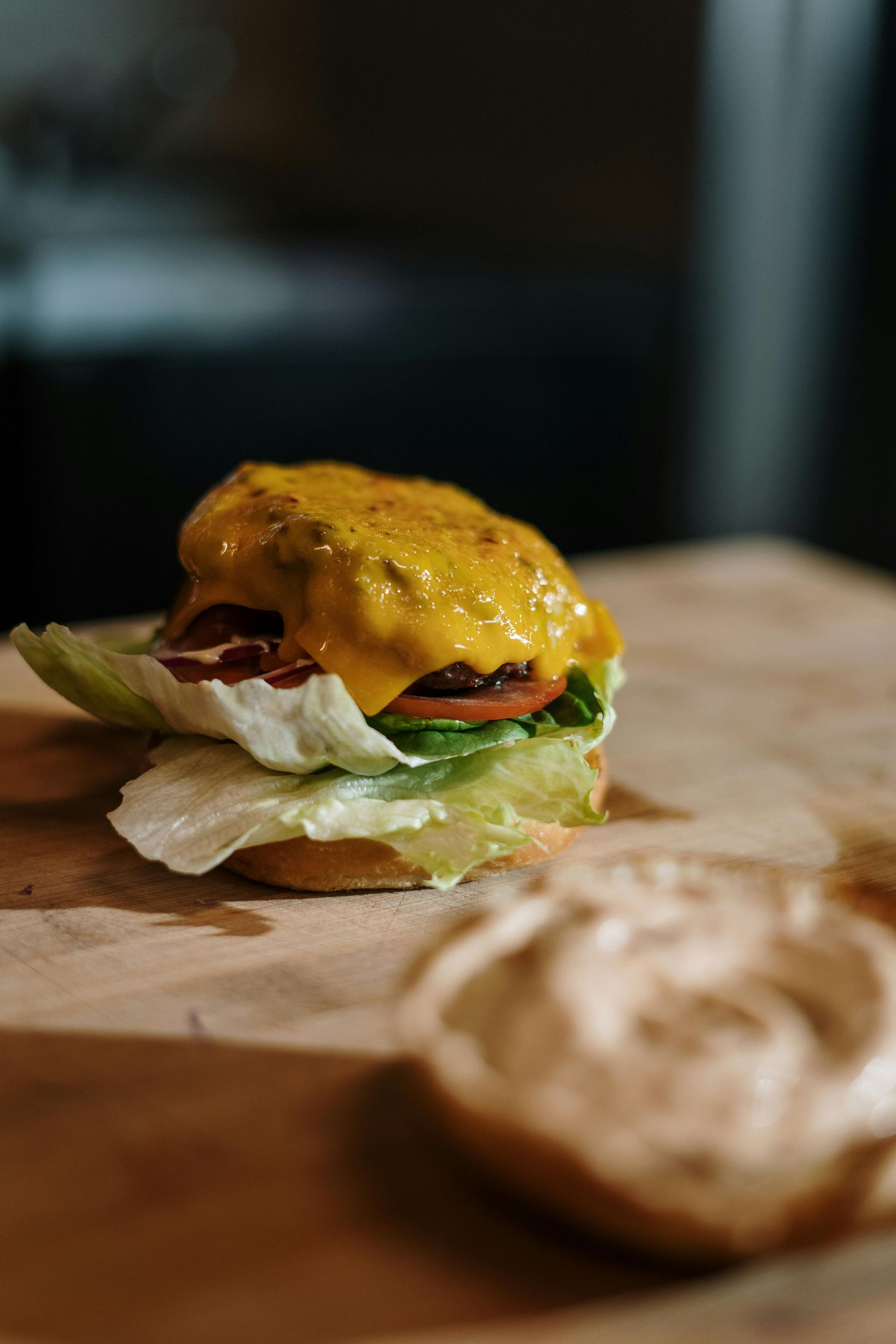 A close up of a hamburger on a bun on a wooden cutting board.