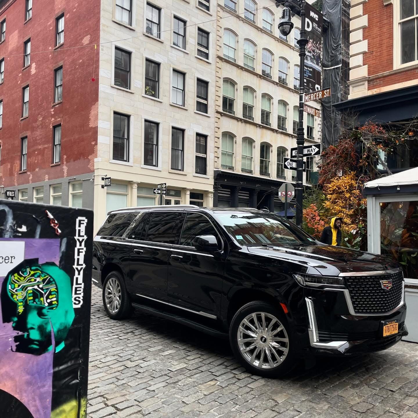 Black Cadillac Escalade SUV parked in front of a modern building.