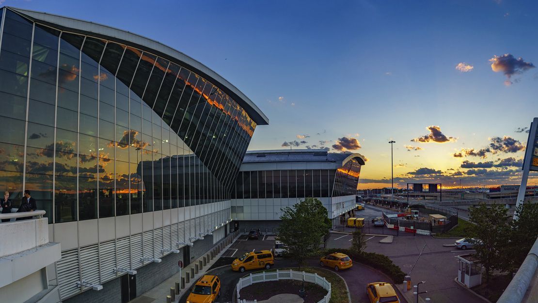 A birdlike white building with curved wings, the TWA Hotel, set against a clear blue sky.