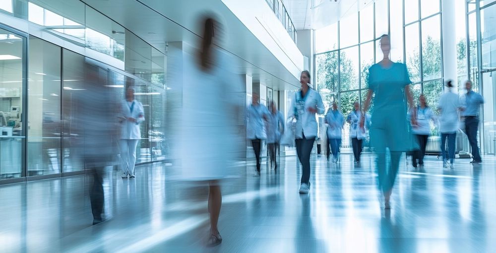 Blurred view of medical staff walking in a hospital hallway.