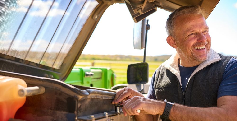 Man smiling next to a tractor, outdoors.