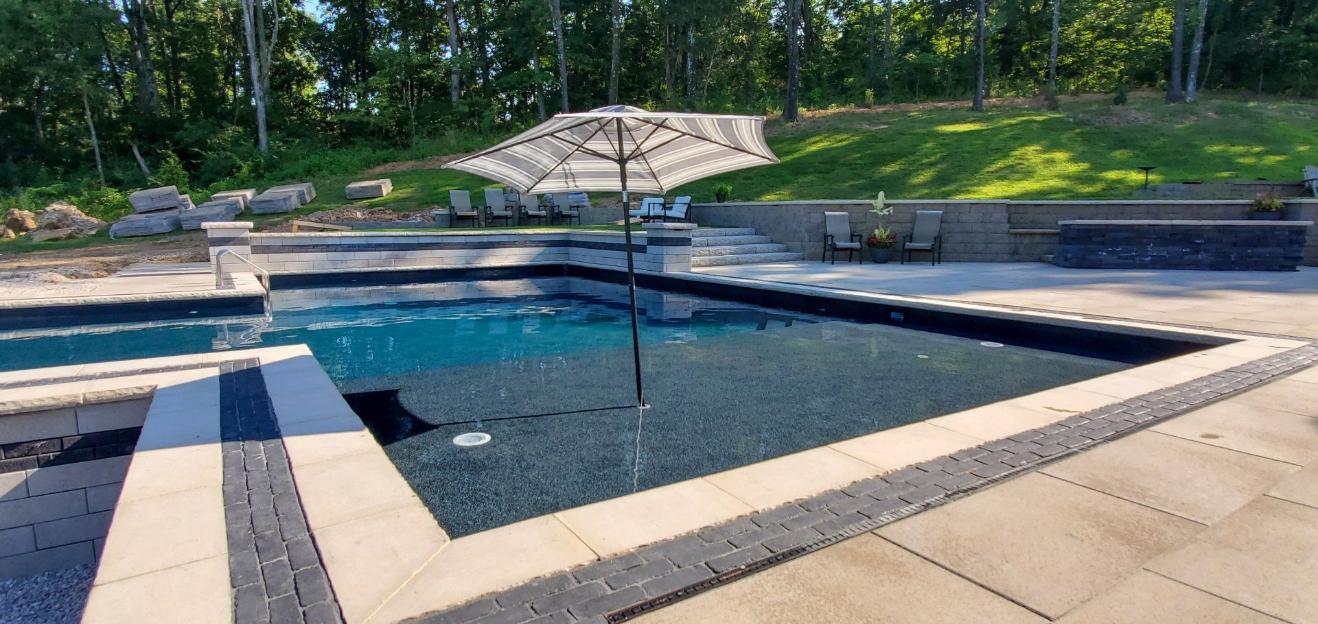 A large swimming pool with a large umbrella in the middle of it.