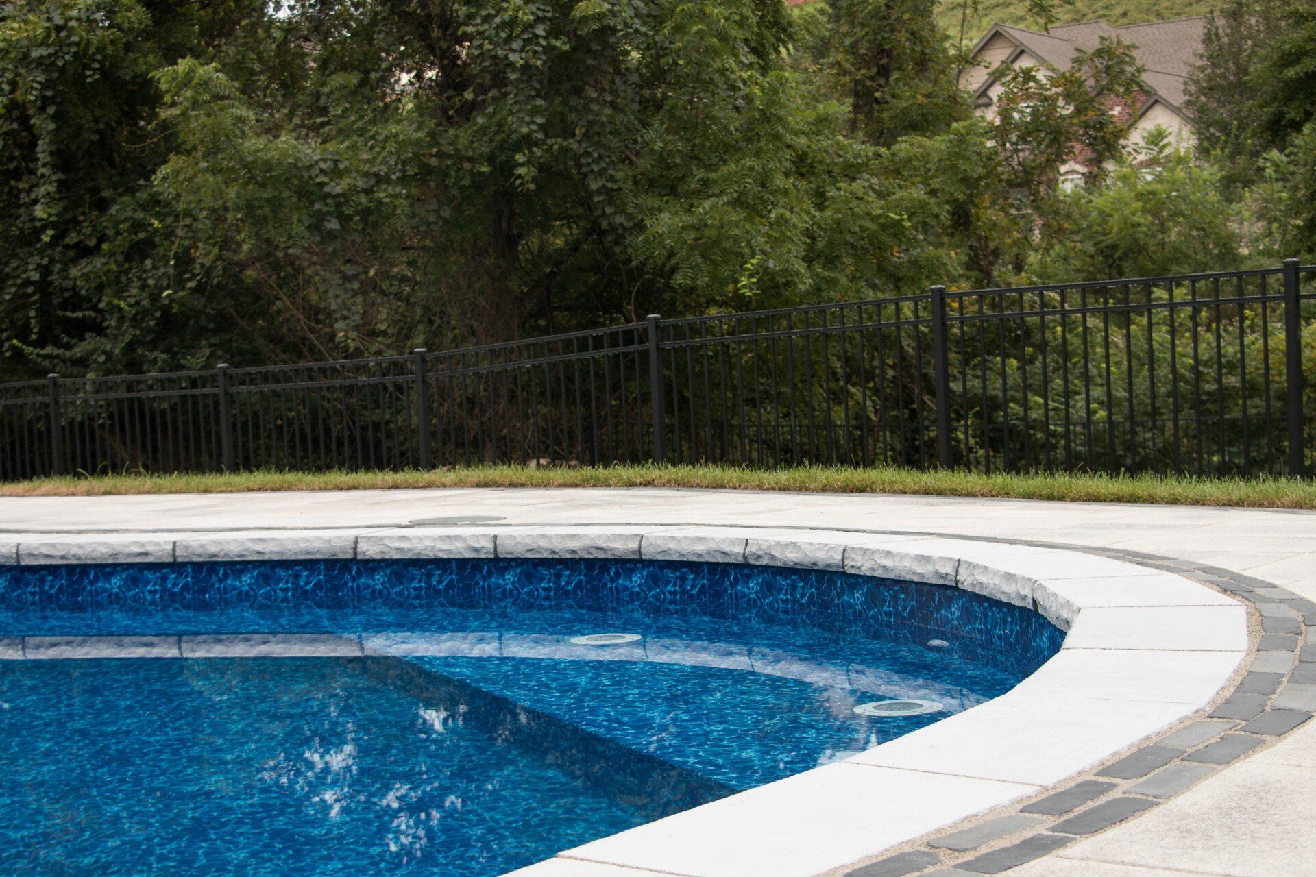 A swimming pool with a fence around it and trees in the background.
