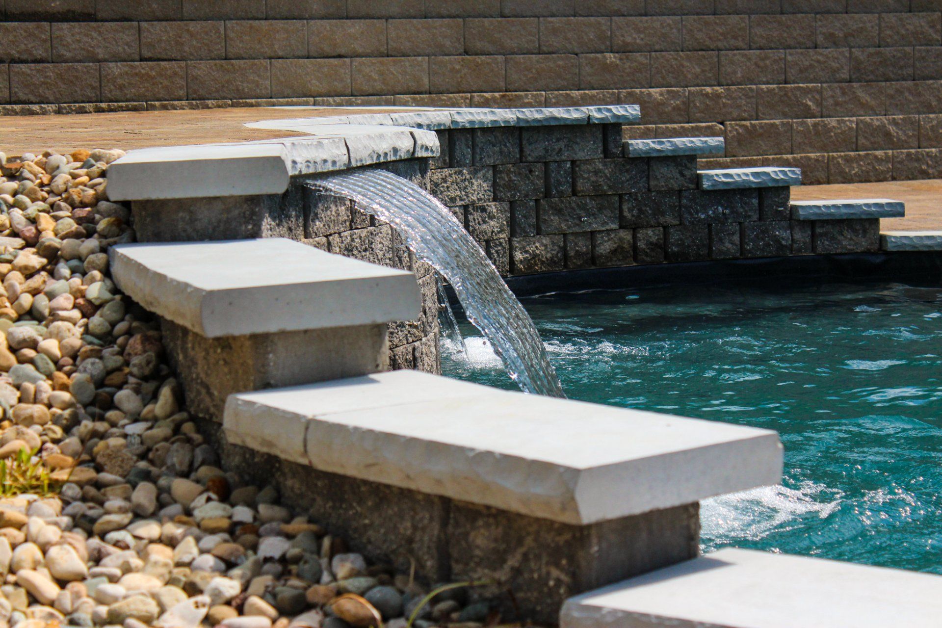 A waterfall in a swimming pool with steps leading to it