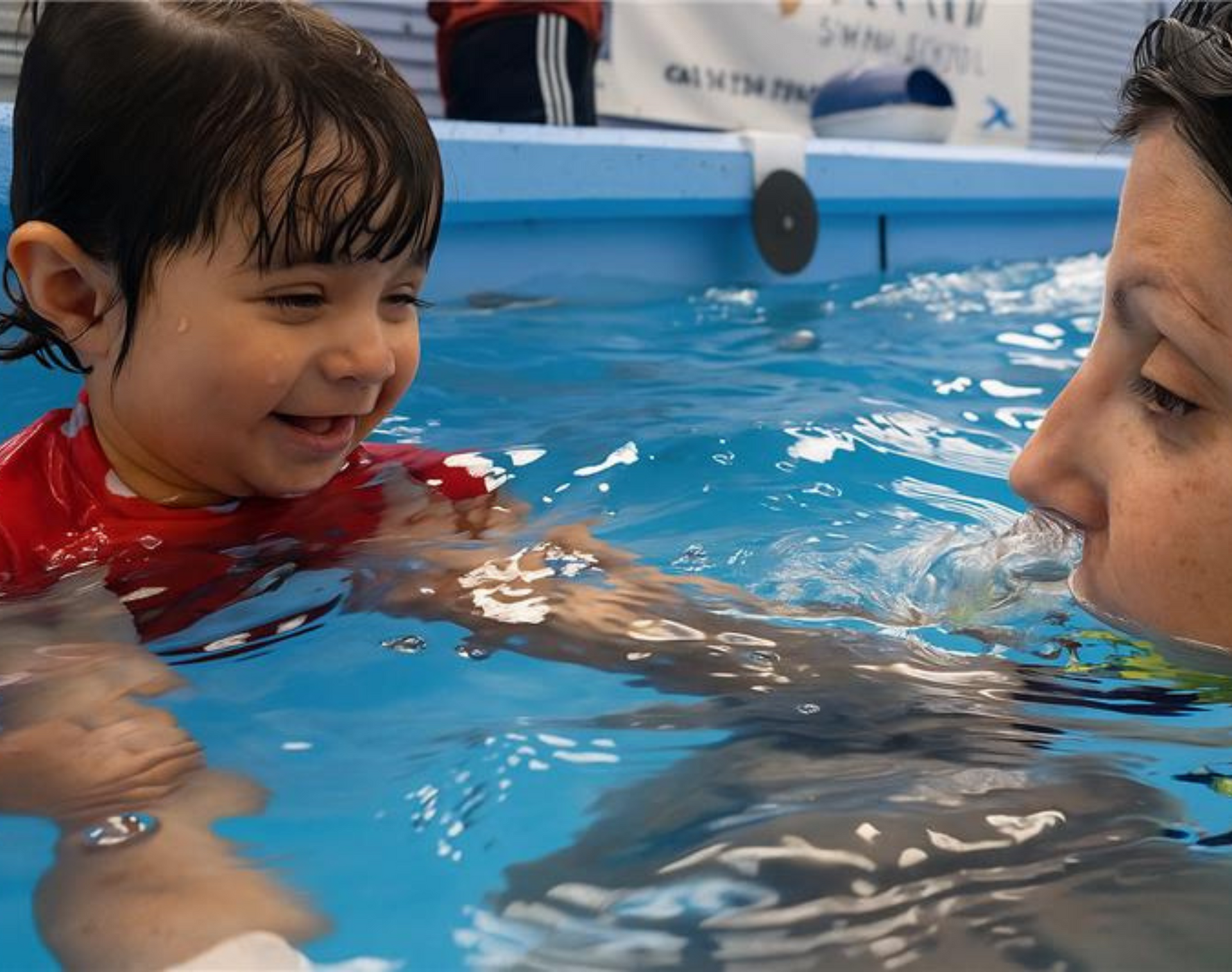 A Child in the pool held by a swimming instructor. 
