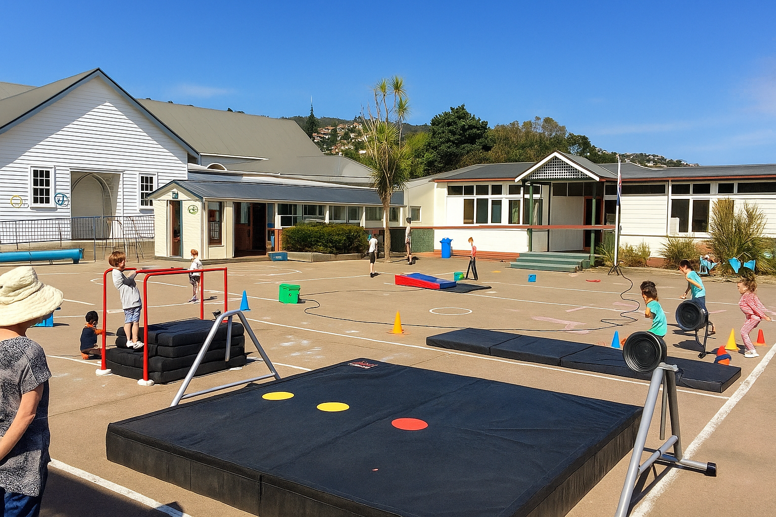 Children on a sunny school playground, engaged in an obstacle course with mats and structures.