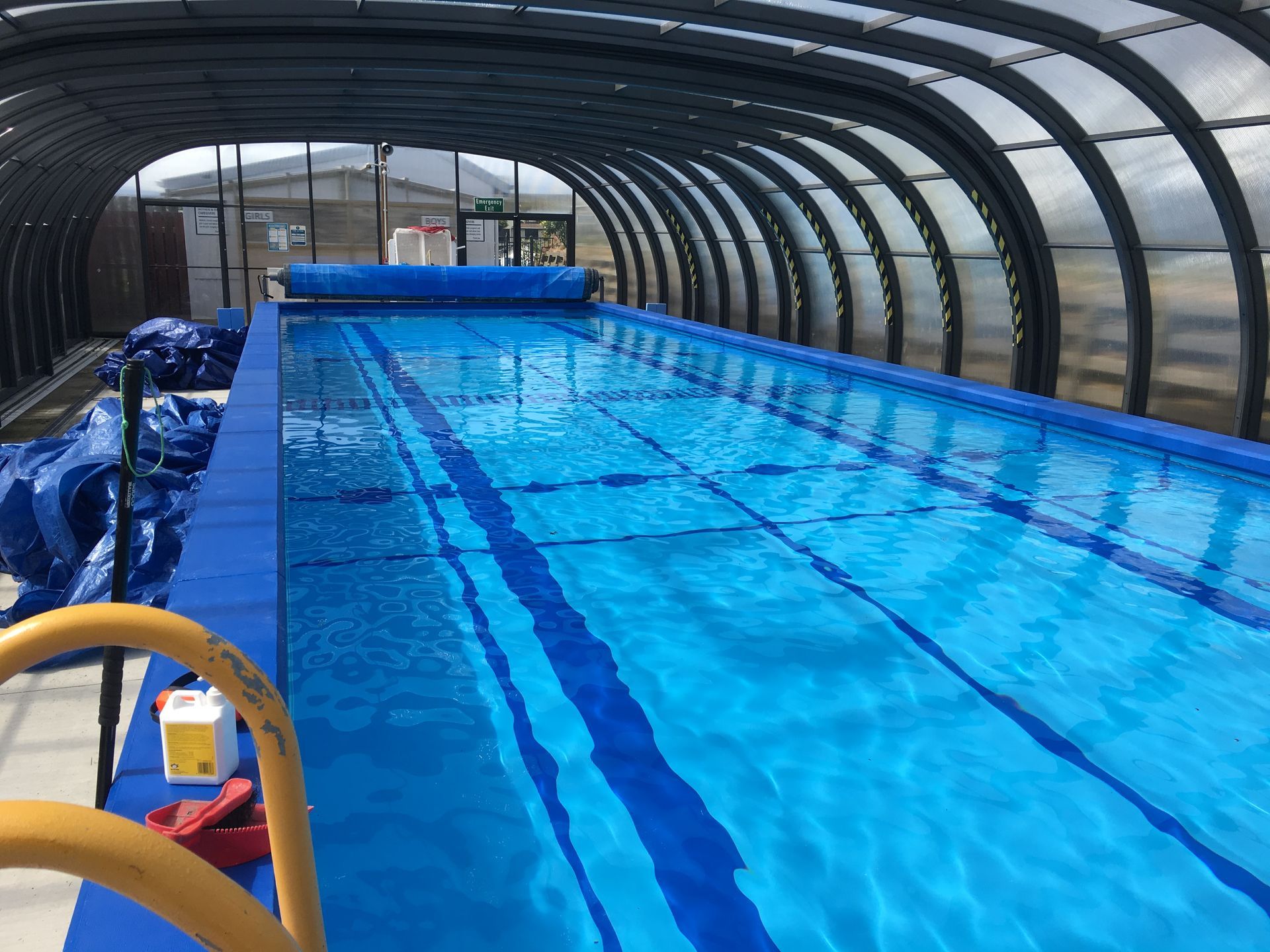 Indoor swimming pool with blue water, lane markers, and a curved roof.
