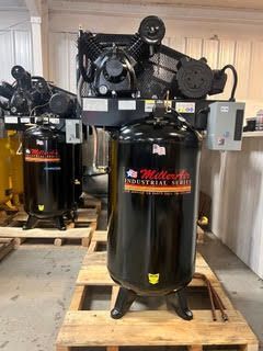 A large black air compressor is sitting on top of a wooden pallet.