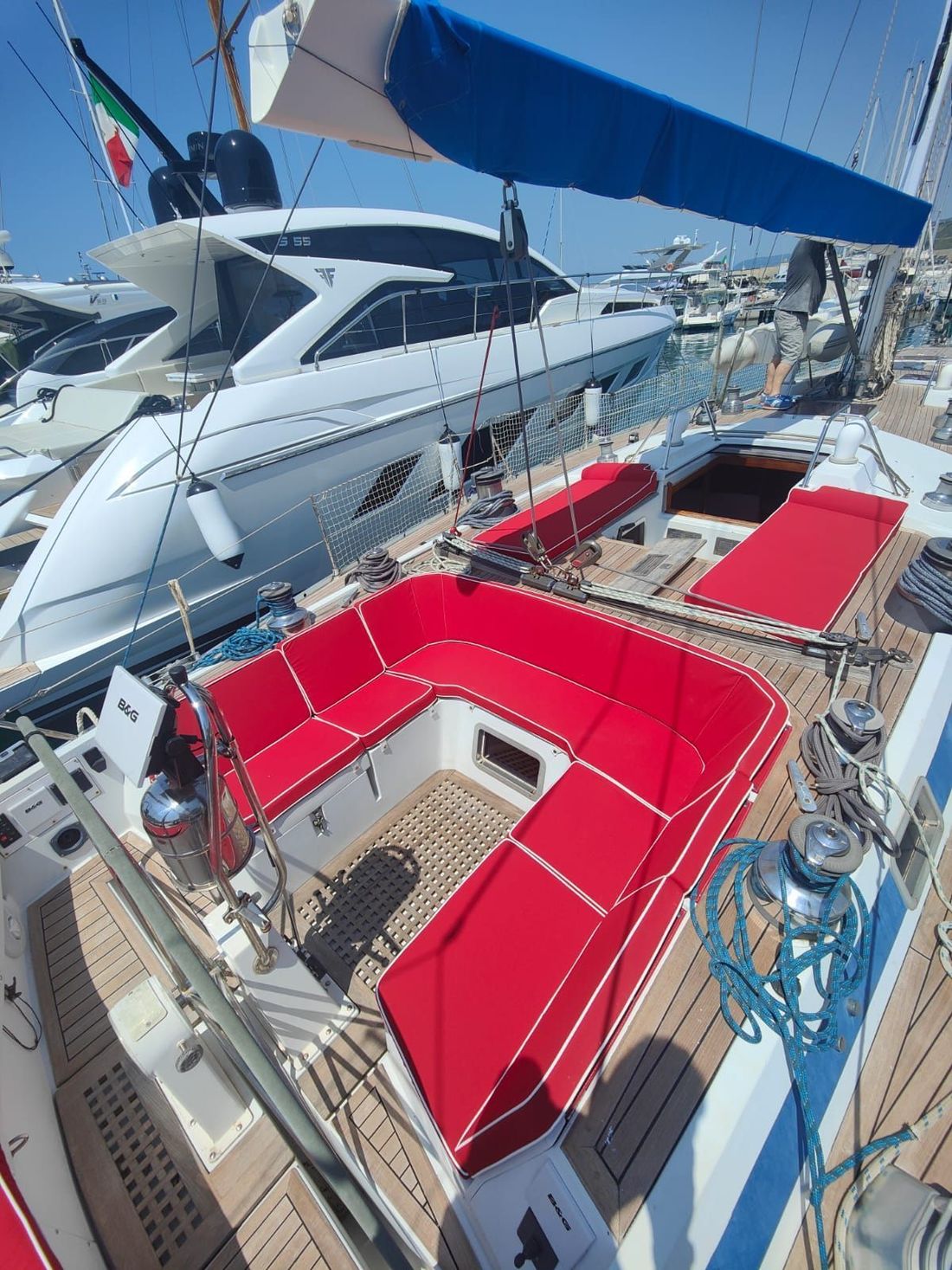 Pontile per barche a vela con cuscini rossi in un porticciolo blu e yacht ormeggiati nelle vicinanze