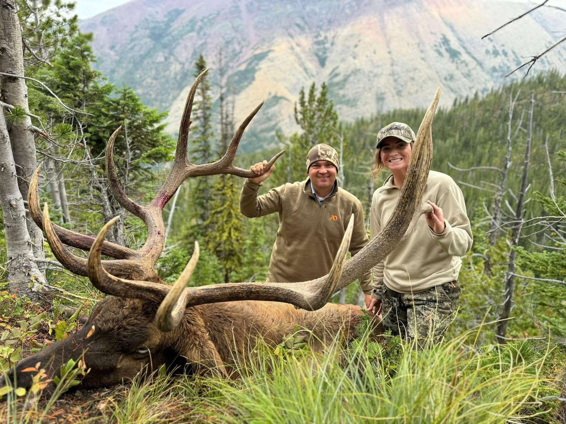 A man and a woman posing with a dead mule deer