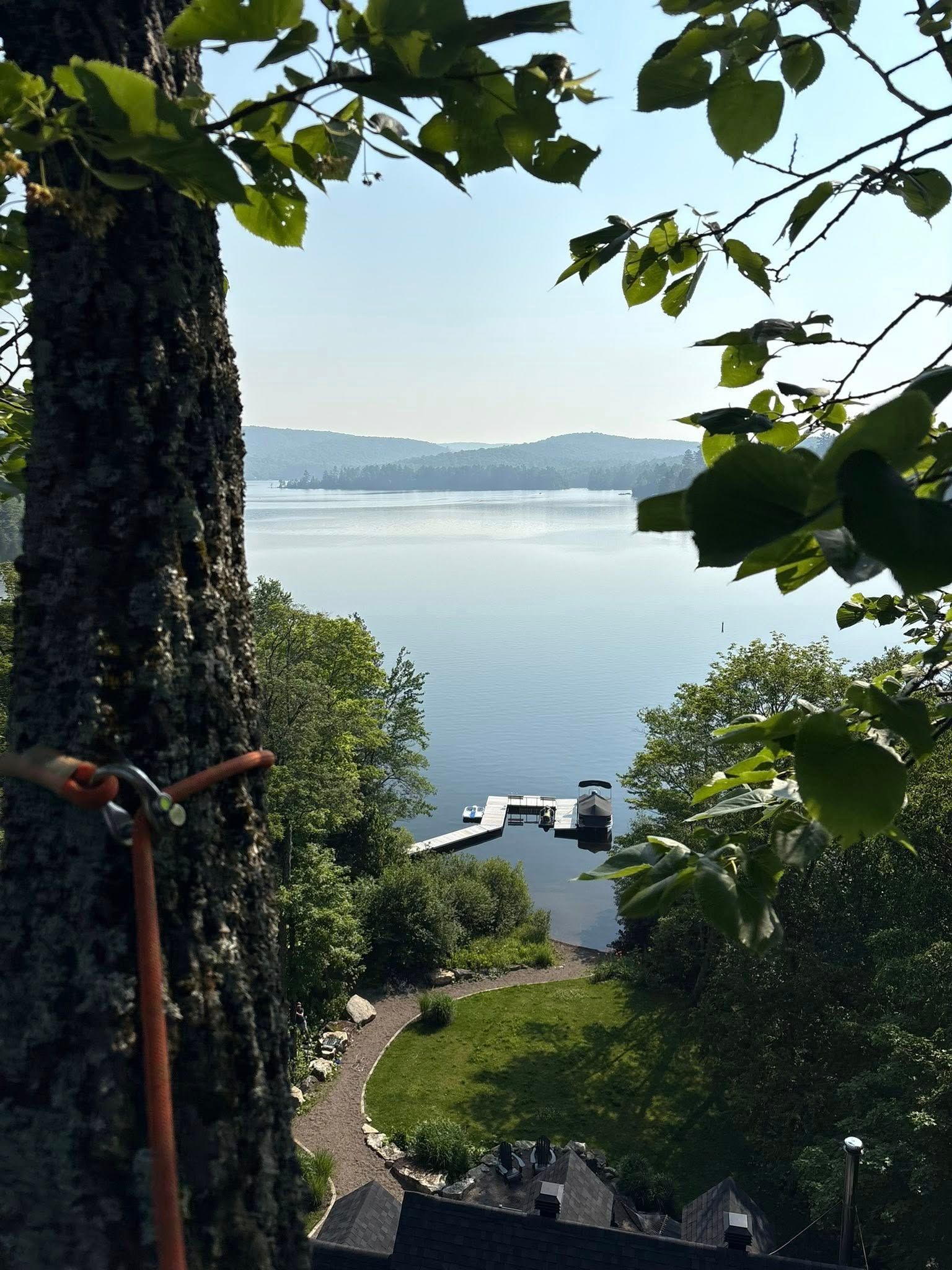 Vue sur le lac encadrée par des branches d'arbres. Un quai s'avance dans l'eau.