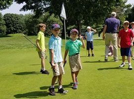 A group of young boys are standing on a golf course.