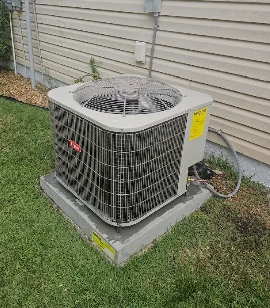 Bryant air conditioning unit on a concrete pad near a house with beige siding and green grass.